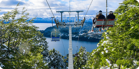 Duas pessoas desfrutando de um passeio em um teleférico nas montanhas nevadas.